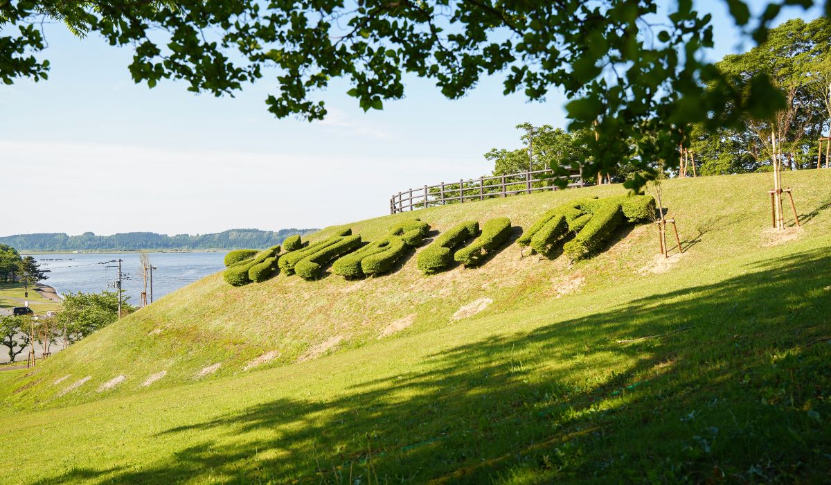 小さな丘に植えられた芝の文字「ふれあい村」